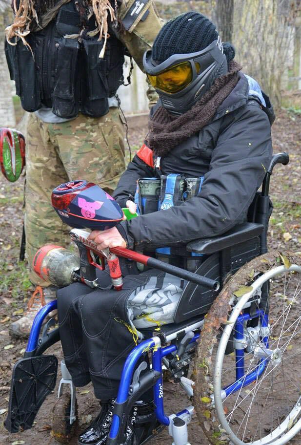 Un joueur en fauteuil roulant lors d'une session de paintball, équipé et prêt à jouer.